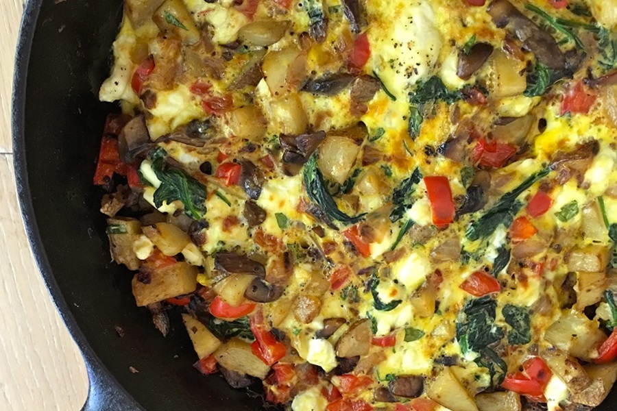 Jillian Michaels Spinach Frittata Recipe Close Up of a Skillet Filled wth Frittata Topped with Spinach, Cheese, and Potatoes