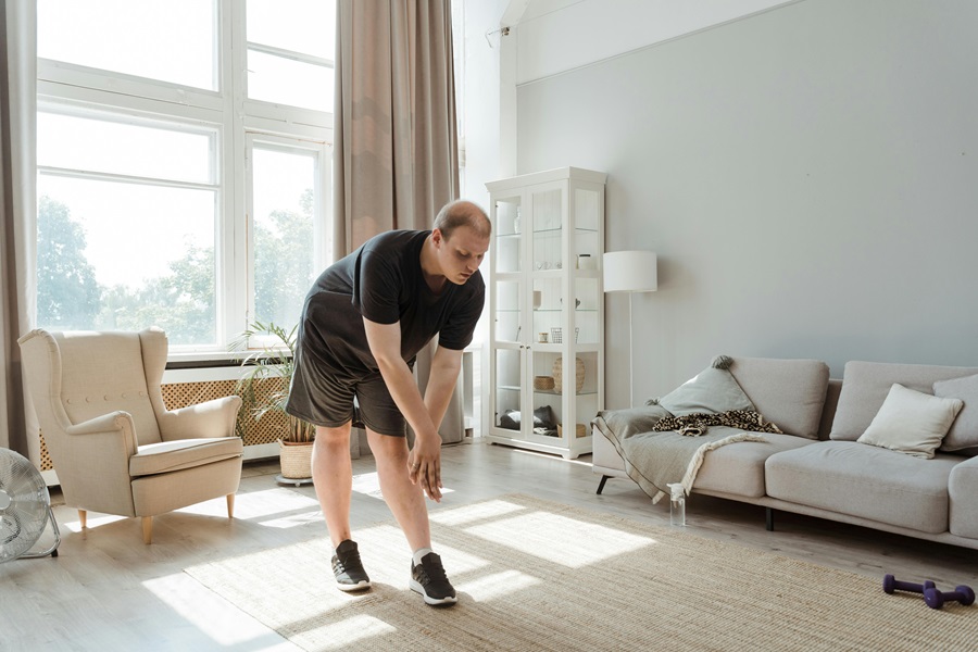 Shaun Week Workouts a Man Wearing Workout Clothes Leaning Down in a Stretch to Touch His Toes