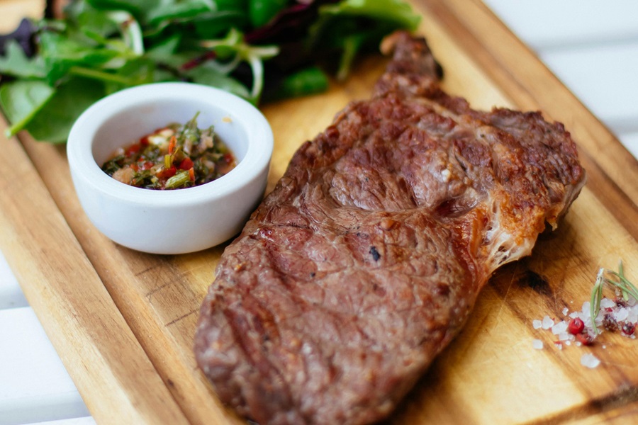 Low Carb Keto Crockpot Recipes for Lunch a Steak on a Wooden Cutting Board with a Spinach Salad