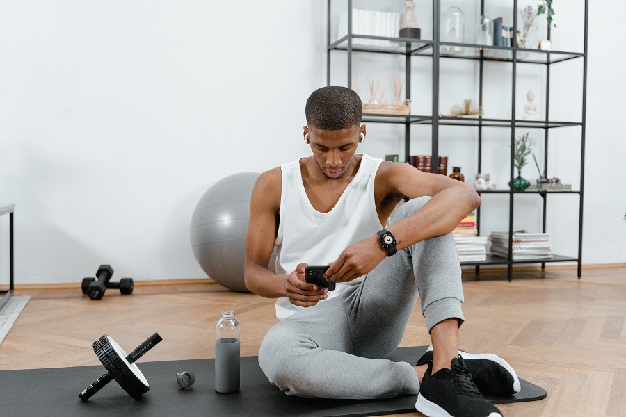 21 Day Fix Workout Order a Man Sitting on a Yoga Mat Preparing a Workout Video on His Phone