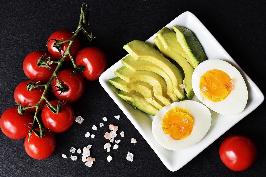 Ketogenic Diet Food List Hard Boiled Eggs, Avocado, and Tomatoes Sliced on a Plate