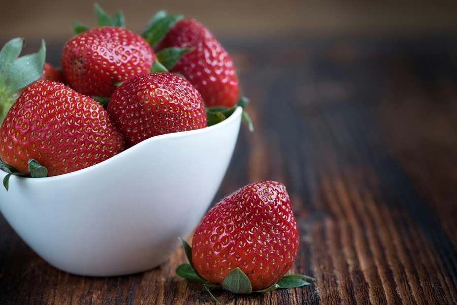 Fresh Strawberry Margarita Recipe on the Rocks Close Up of a White Bowl of Strawberries on a Wooden Surface