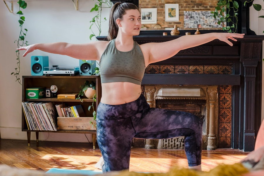 35 At Home Workouts for Women a Woman Doing a Workout in a Living Room with a Bookshelf in the Background