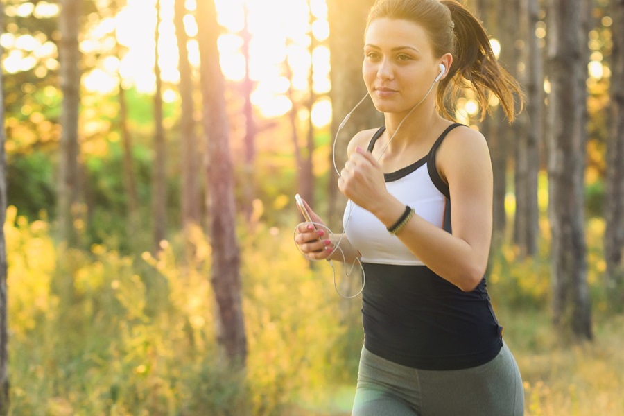 35 At Home Workouts for Women a Woman Wearing Workout Clothes and Headphones Running Through a Forest