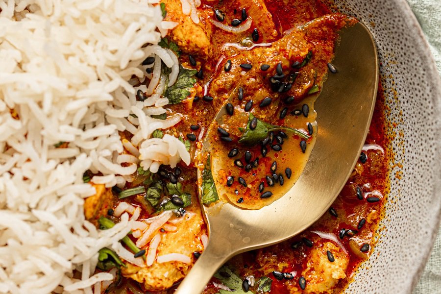 Easy Chicken Tikka Masala Recipe with Coconut Milk Close Up of a Spoon in a Bowl of Chicken Tikka Masala with Basmati Rice
