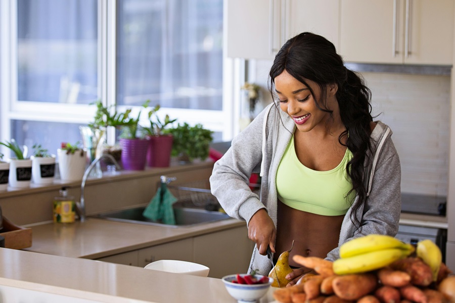 Why Does Intermittent Fasting Work a Woman in a Kitchen Cutting Fruit for a Healthy Snack